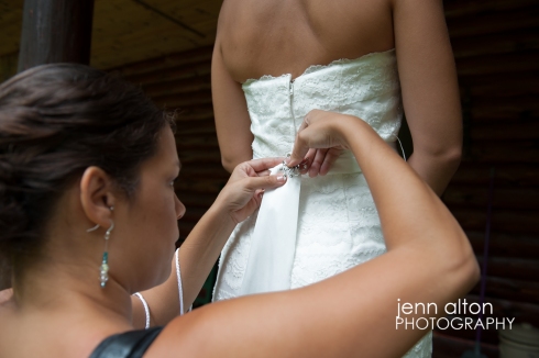 Bridesmaid pinning brooch to brides dress as a final detail, cape cod wedding